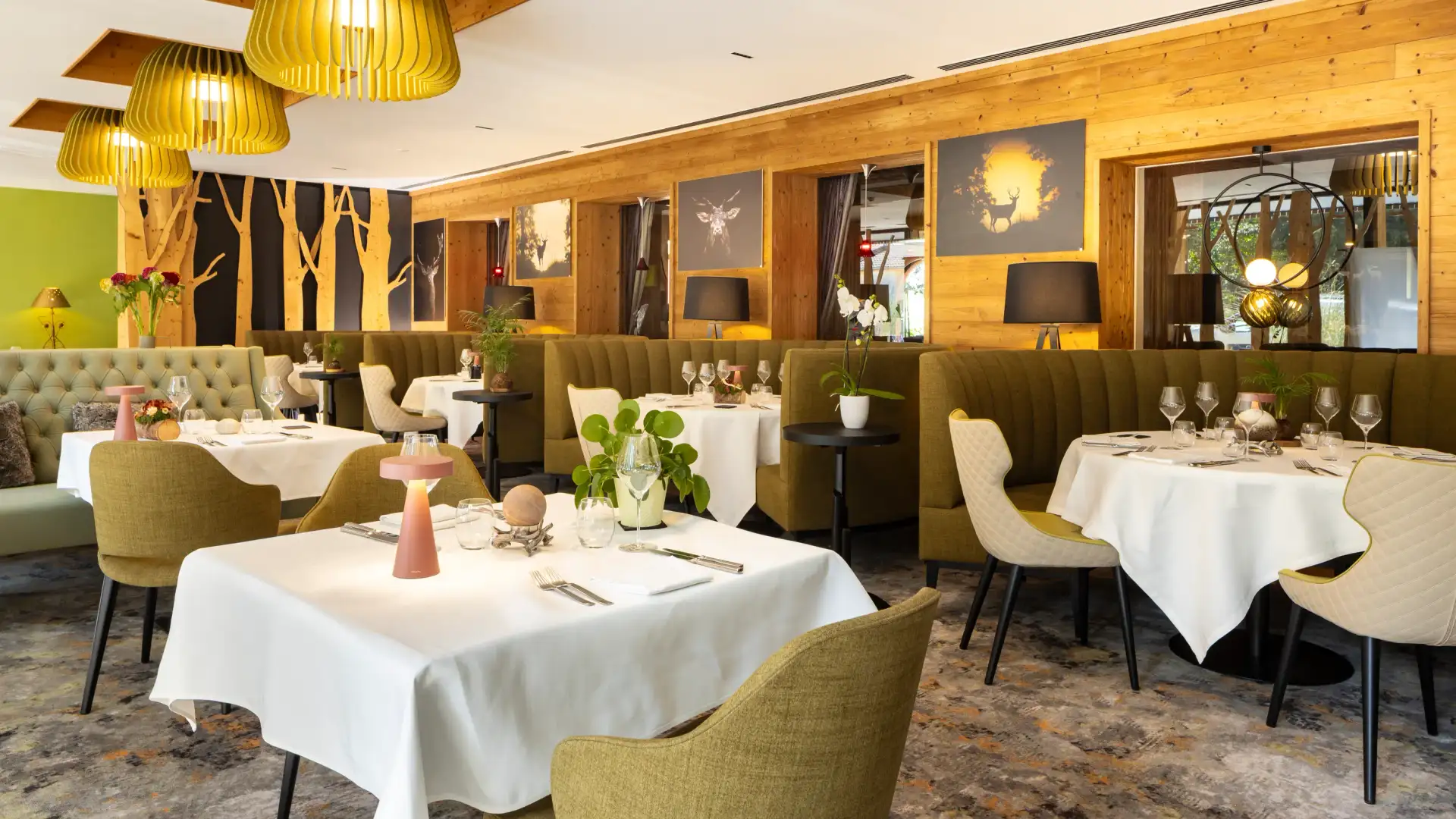 Restaurant élégant avec des tables dressées, des chaises vertes, des luminaires jaunes et des murs en bois