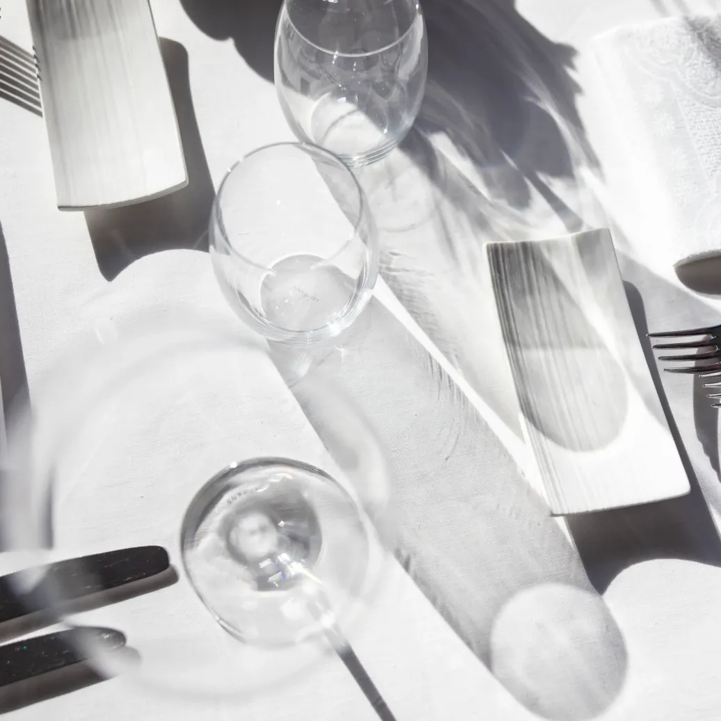 Table dressée avec des verres, des couverts et des serviettes en papier sous la lumière du soleil