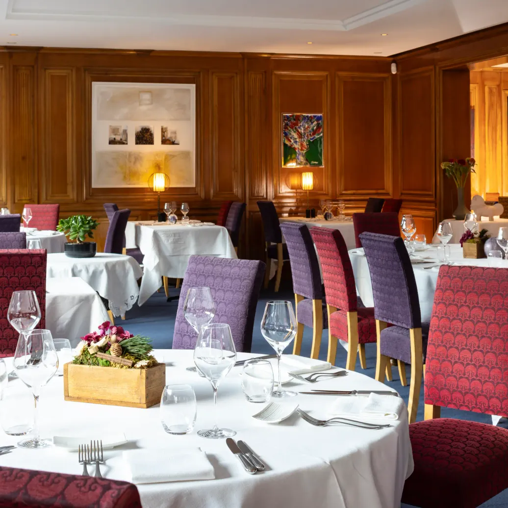 Salle de restaurant élégante avec tables dressées, chaises rembourrées et œuvres d'art sur les murs