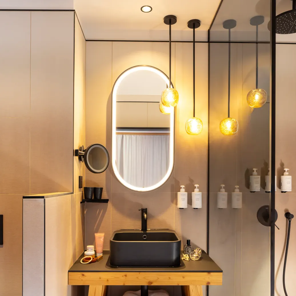 Salle de bain moderne avec lavabo noir, miroir ovale et douche à effet pluie