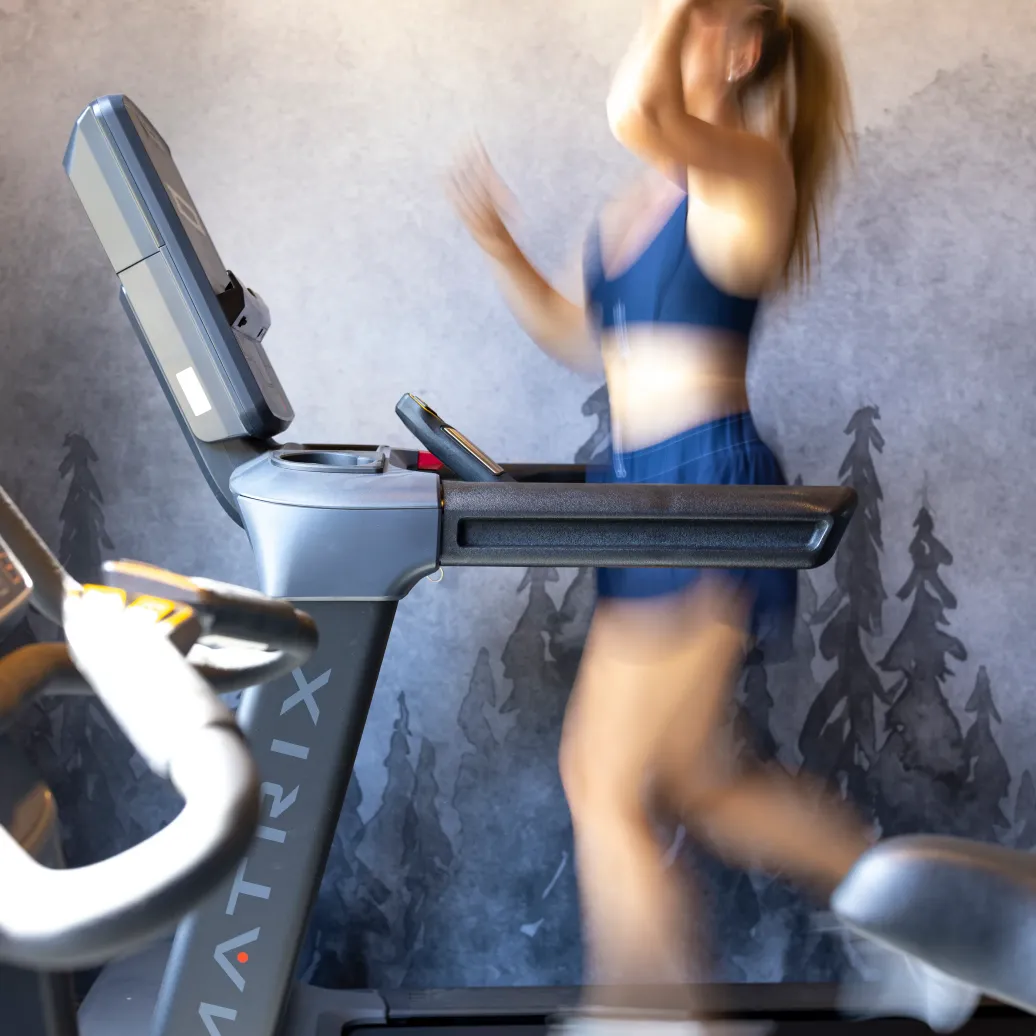 Une personne fait du jogging sur un tapis de course dans une salle de sport