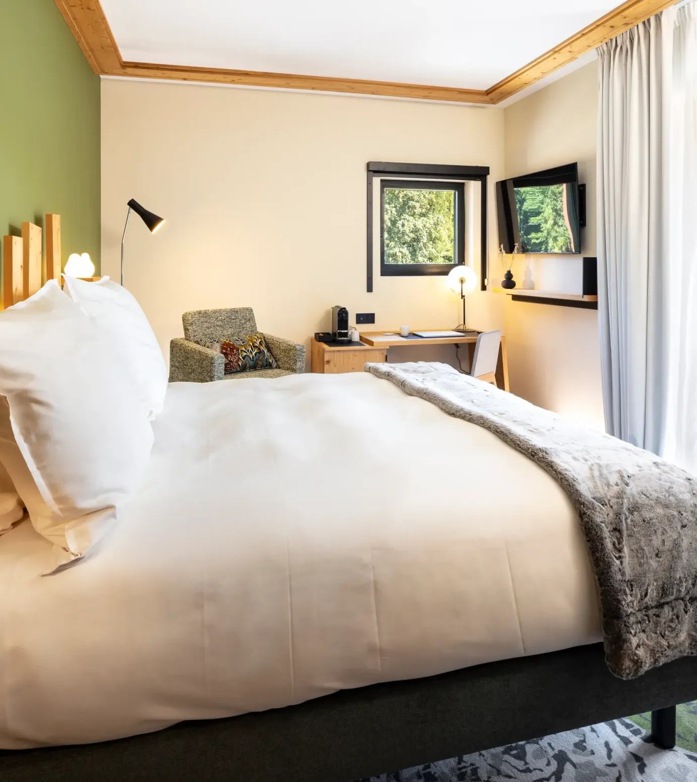 Chambre avec un lit double, une table de chevet, un bureau, des fenêtres avec vue sur l'extérieur et une porte vitrée donnant sur un balcon