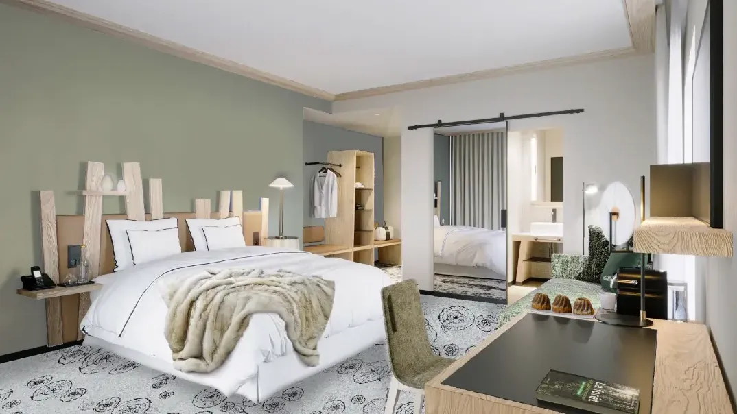 Chambre moderne avec un grand lit blanc, une couverture beige, des tables de chevet en bois, un coin bureau et un dressing visible à travers une porte ouverte