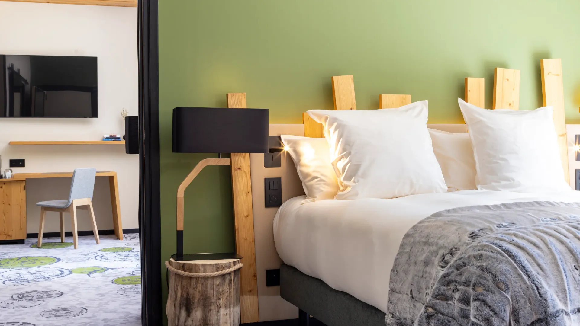 Chambre d'hôtel avec un lit double, une lampe de chevet en bois, une télévision et un bureau avec une chaise