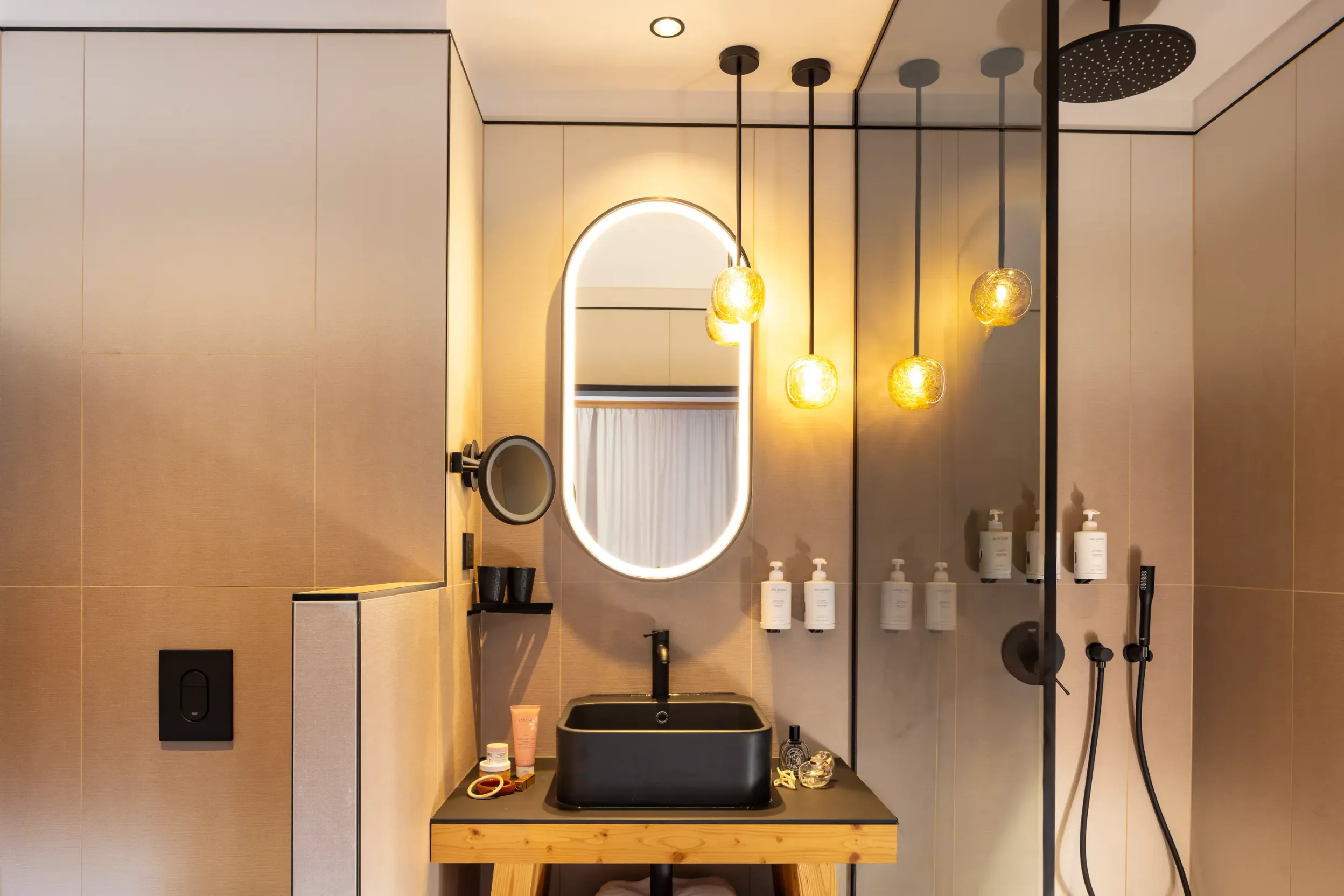 Salle de bain moderne avec lavabo noir, miroir ovale et douche à effet pluie