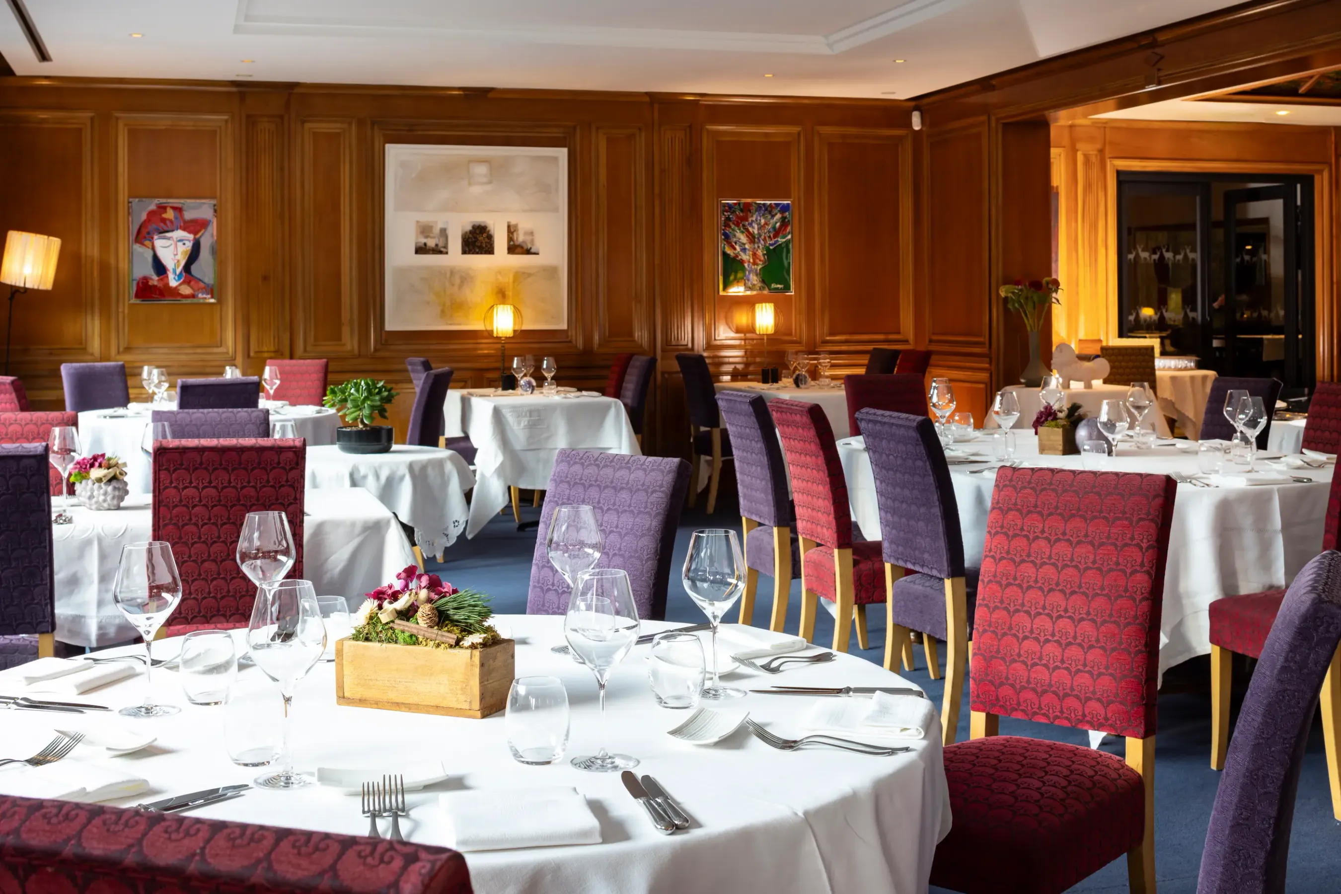 Elegante Restauranträume mit gedeckten Tischen, gepolsterten Stühlen und Kunstwerken an den Wänden