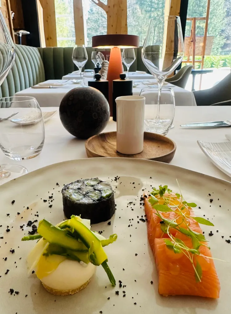 Assiette de plats fins avec sushi, saumon et légumes, posée sur une table élégante avec verres à vin et décoration